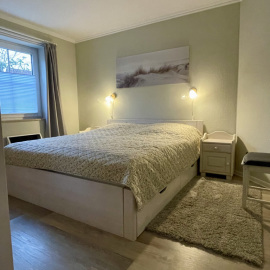 Helles Schlafzimmer mit gemütlichem Doppelbett und Fenster