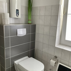 Helles Bad mit WC, Waschbecken, zeitloser Fliesengestaltung und Fenster